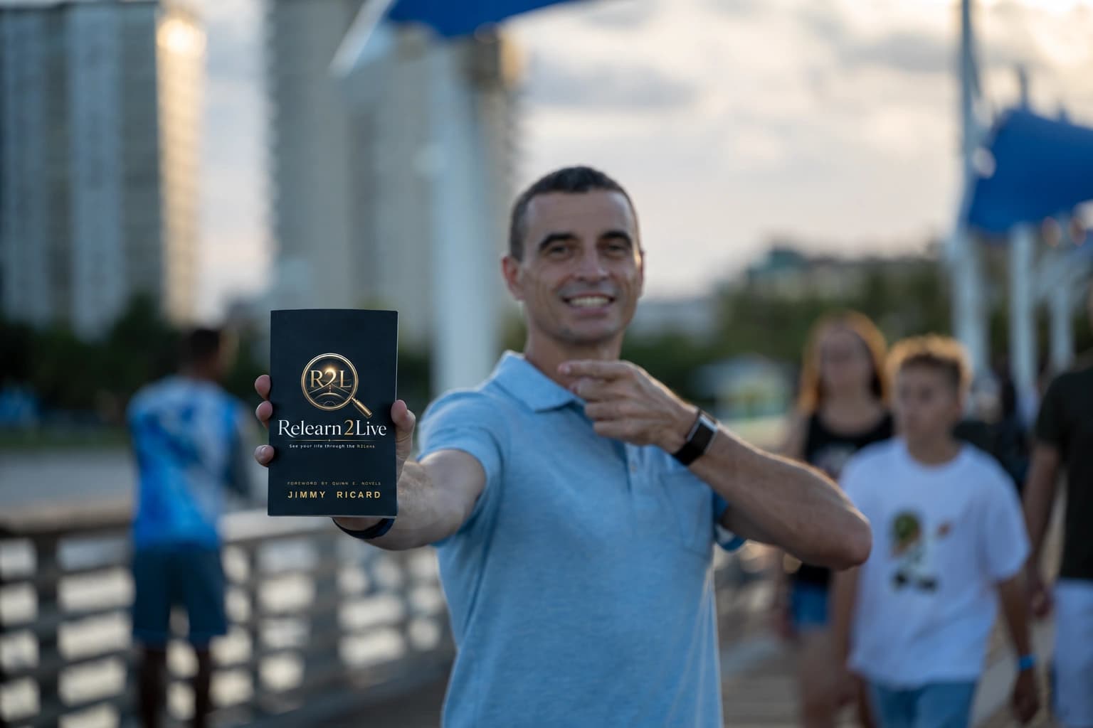 Jimmy Ricard holding Relearn2Live, with the book in focus and Jimmy softly blurred behind it